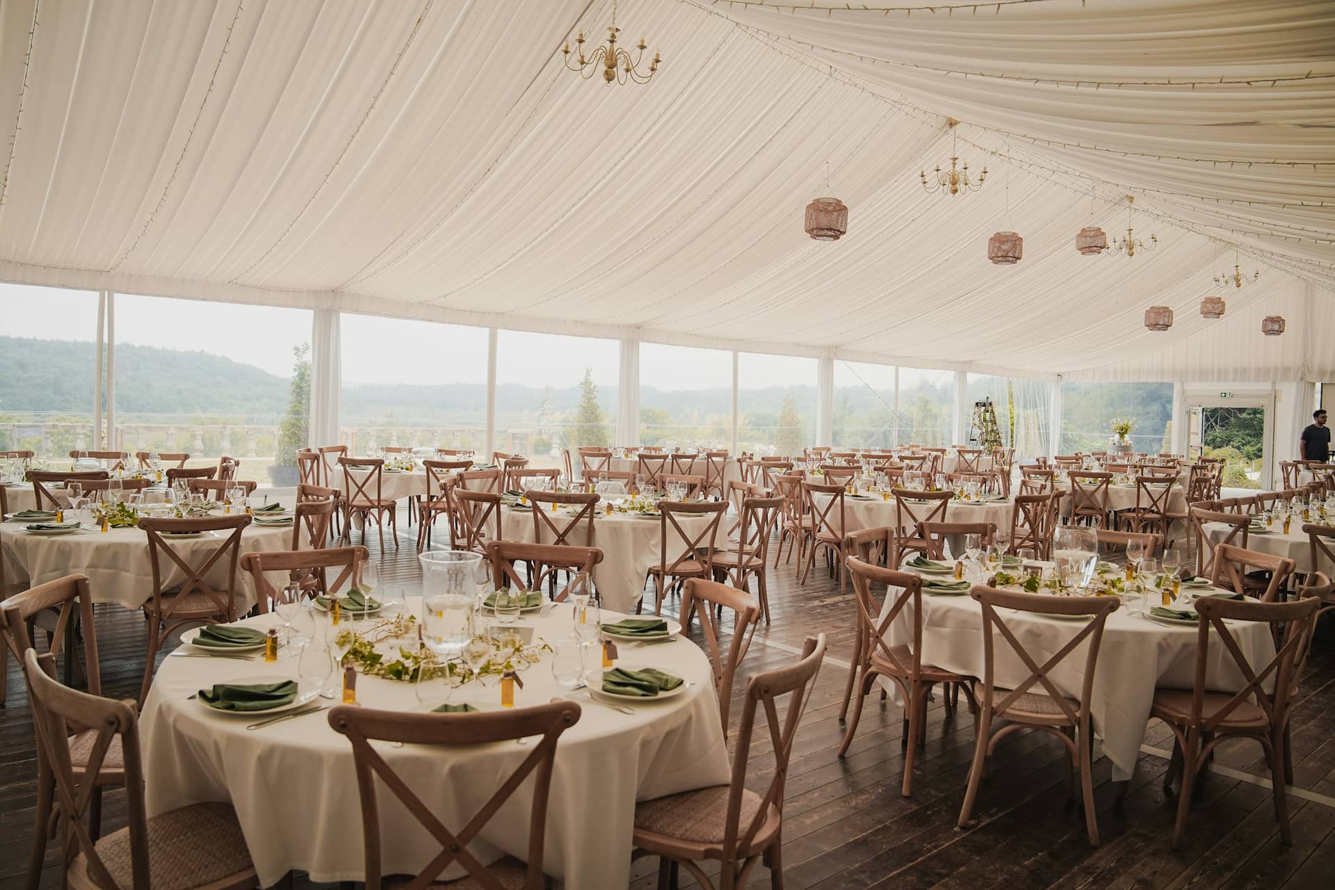 Round tables set for a reception under a marquee